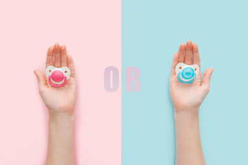 partial view of women holding pacifiers with or lettering on blue and pink background