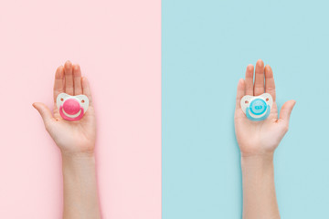 partial view of women holding pacifiers on blue and pink background with copy space