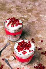 Healthy dessert with organic red currants, fresh yogurt and corn flakes. Dietary breakfast on a brown background