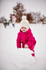 Fototapeta na wymiar Little girl is playing with snow and rejoicing