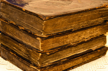 Stack of old and worn leather cover books with gold leaf embossing