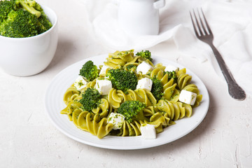 Tasty dinner. Green  pasta with broccoli, feta cheese and herb sauce on a white background.