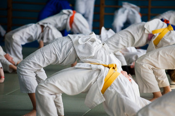 Children do physical exercises during warm-up in judo training