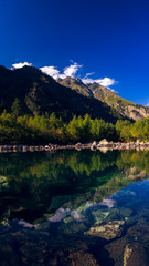 A huge panorama of the High-mountainous Baduk lake among the high Caucasian mountains and beautiful trees. Sunny summer day.