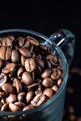 Glass cup of coffee beans on black background