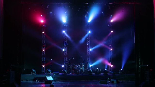 Colorful light flashing and white rays on an empty stage in the dark. Stage lighting. Light show.