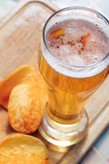 The beer style . glass of beer with potato chips on wooden background.