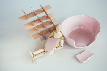 Creative concept. Wooden man with broken plate . Problems, psycho-emotional experiences, without exit, depression - a concept for the emotional state of people.