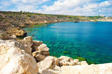 Rock coastline near deep green transparent emerald water