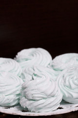 Obraz na płótnie Canvas Homemade marshmallows laid on a plate. Marshmallow with mint, with a green tint. On a dark background.