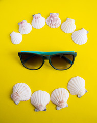 Obraz premium Semicircle of white seashells with sunglasses on yellow background