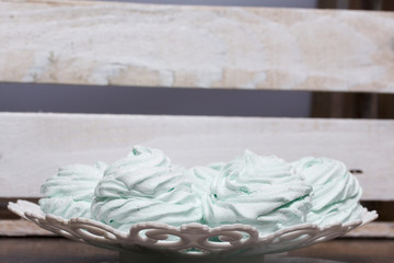 Homemade marshmallows laid on a plate. Marshmallow with mint, with a green tint. On the background of wooden boards.