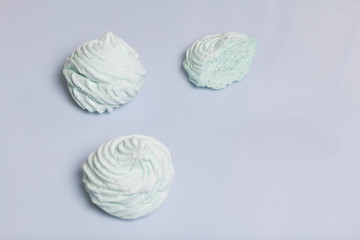 Homemade marshmallows laid on a white background. Marshmallow with mint, with a green tint. Nearby is a piece of marshmallow, its slice is visible.