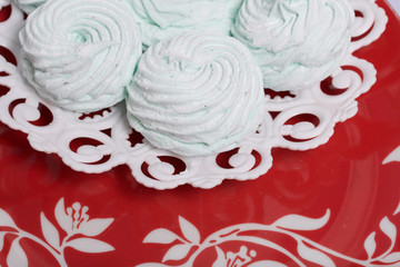 Homemade marshmallows laid on a plate. Marshmallow with mint, with a green tint. On the red background.
