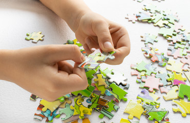Close up of child's hands playing with colorful puzzles on light table. Early learning.