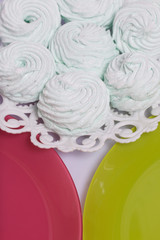 Homemade marshmallows laid on a plate. Marshmallow with mint, with a green tint. Nearby are plates of pink and light green.