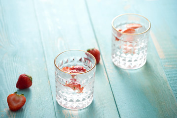Glass of fresh, cold infused water with fresh strawberries and  fresh strawberries next to it