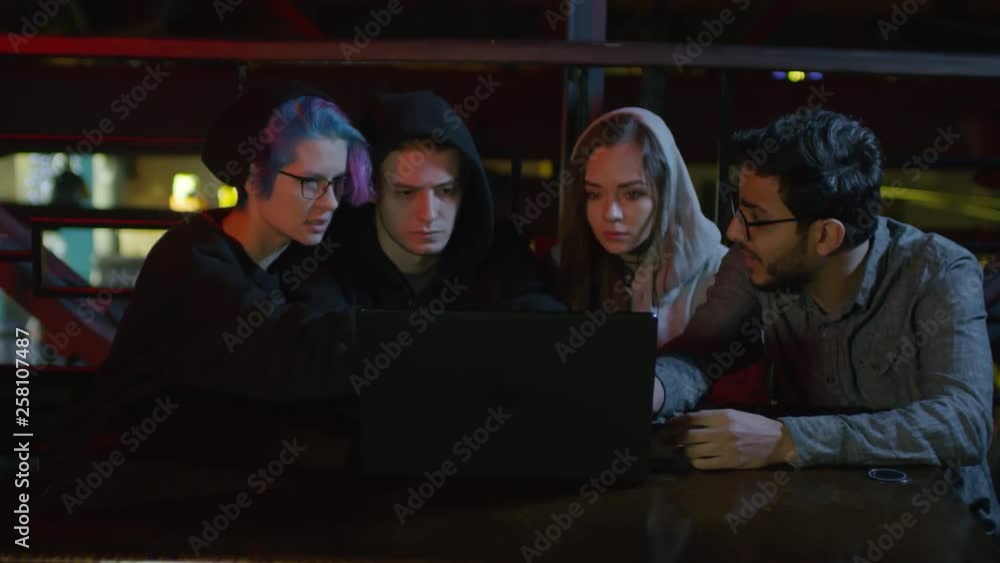 Poster zoom in of four teenagers sitting at café table at pc and discussing program code