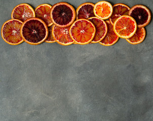 Blood juicy Sicilian orange slices on gray background. Sliced blood orange texture. Citrus...