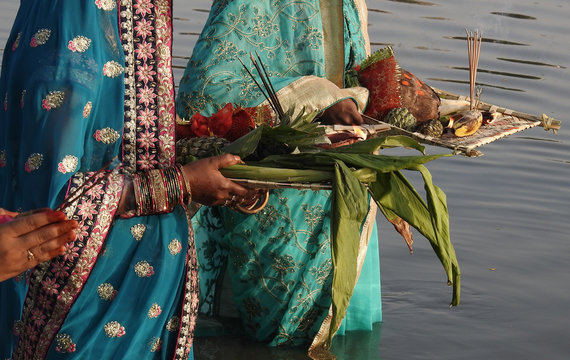 Hindu women pray sun God, with food offerings, at dusk,in the bank of lake, during annual ritual Chhath Puja