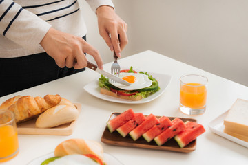 With a fork and knife a sandwich is cut. sandwich with eggs and meat