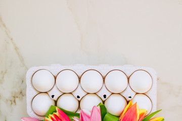 Easter concept, flat lay chicken eggs and colorful tulips on marble background. Top view.