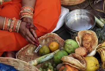 Hindu woman pray sun God, with food offerings, at dusk,in the bank of lake, during annual ritual...