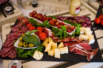Meat dish with ham, crackers, tomatoes, olives and sausage