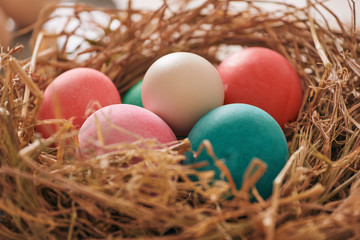 Beautiful Easter multi color egg in straw on wooden background, Easter day concept
