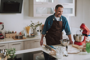 Happy bearded man laughing while looking at the mixer