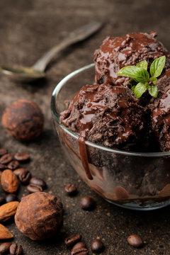 Chocolate ice cream with liquid chocolate with almonds and coffee beans on a dark background. close-up