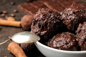 Chocolate ice cream with liquid chocolate with a cinnamon stick and coffee beans on a dark background.