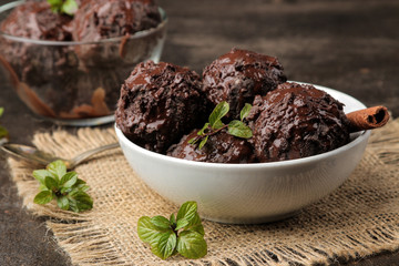 Chocolate ice cream with liquid chocolate with a cinnamon stick on a dark background.