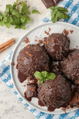 Chocolate ice cream with liquid chocolate on a light concrete background. top view