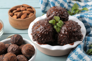 Chocolate ice cream with liquid chocolate and with a cinnamon stick, coffee beans and almonds on a blue wooden background.