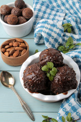 Chocolate ice cream with liquid chocolate and with a cinnamon stick, coffee beans and almonds on a blue wooden background.