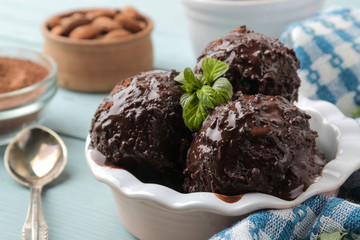 Chocolate ice cream with liquid chocolate and with a cinnamon stick, coffee beans and almonds on a blue wooden background.