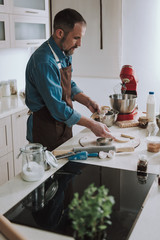 Concentrated man having raw cookies on the table