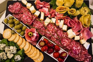 Meat dish with ham, crackers, tomatoes, olives and sausage