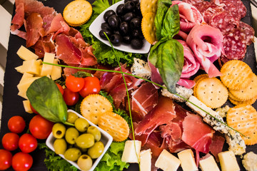 Meat dish with ham, crackers, tomatoes, olives and sausage