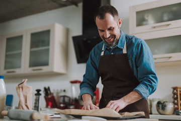 Happy man smiling and looking at the baking paper