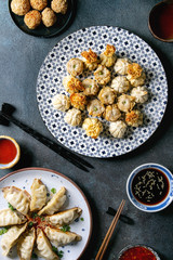 Dim sum Gyozas asian fried dumplings party set with variety of sauces served in ceramic plates and bowls with chopsticks, tea cups over dark blue texture background. Flat lay, space