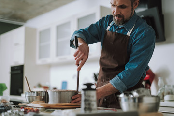 Concentrated man using cake icing spreader while cooking