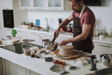 Bearded man using cream ice spreader while taking cream from bowl