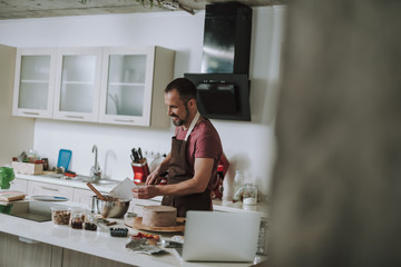 Positive man smiling while smoothing cream on the cake