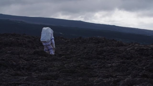 Astronaut walking in a Martian desolate landscape, Hawaii