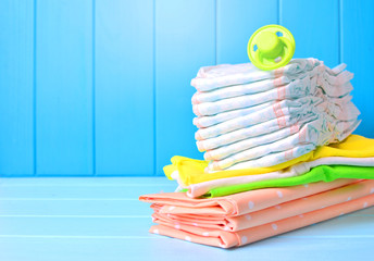 Baby accessories background. Pile of diapers, napkins and dummy.