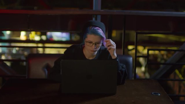 Zoom in of Caucasian teenage girl sitting at laptop in caf&eacute;, thinking and typing on keyboard