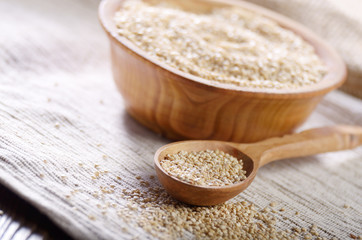 Raw organic superfood gluten free quinoa seeds in wooden spoon and bowl on kitchen table closeup