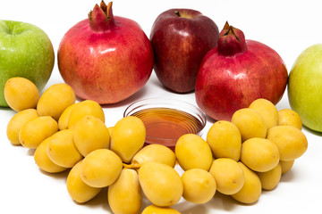 Rosh Hashanah (Jewish New Year) Traditional Symbols, Honey in a glass jar, Pomegranates, Dates, Red And Green Apples. Isolated On A White Background